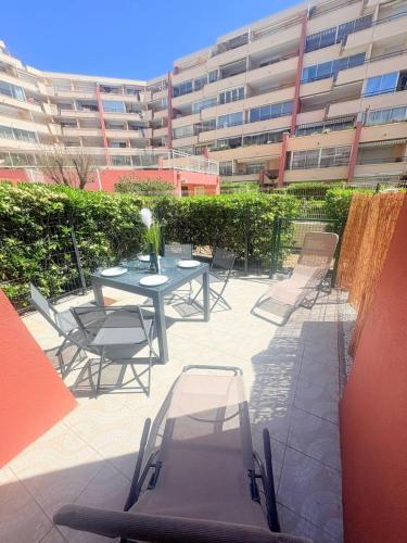 un patio avec une table et des chaises devant un bâtiment dans l'établissement Le Toucan, Front de mer -1 min des plages, à Sète