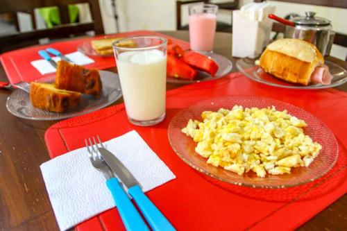 a table with a plate of eggs and bread and milk at Hotel Flamboyant Taubate in Taubaté