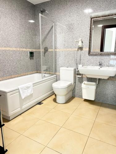 a bathroom with a tub and a toilet and a sink at National Golf Resort in Klaipėda