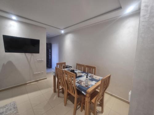 a dining room with a table with chairs and a television at Appartement de luxe in Ifrane