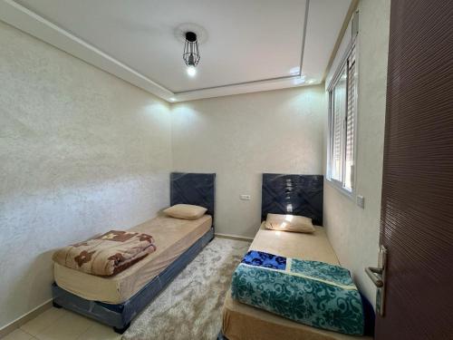 two twin beds in a room with a door at Appartement de luxe in Ifrane
