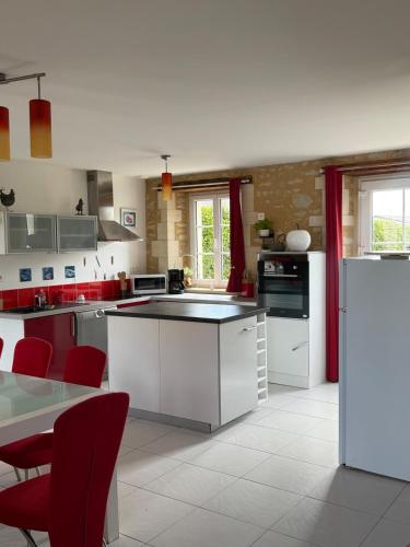 - une cuisine avec des appareils électroménagers blancs et des chaises rouges dans l'établissement Gîtes Fleur des Pommiers, près des plages du débarquement, à Juaye-Mondaye