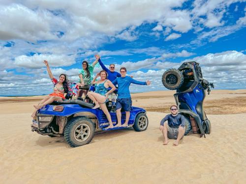 a group of people sitting on the back of a truck in the sand at Tô em Casa Hospedagem in Jijoca de Jericoacoara