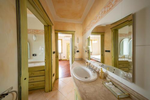 un bagno con un lavandino e un grande specchio di Villa Sun Kiss a Volta Mantovana