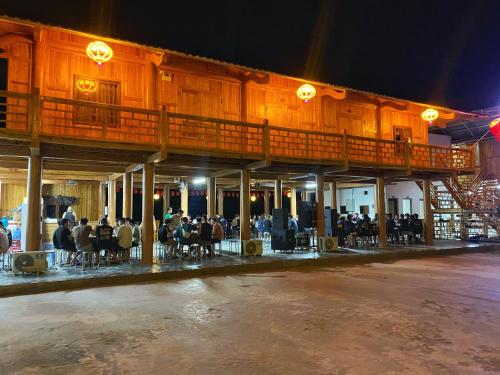 a group of people sitting at tables outside of a building at Na Tau Homestay & Restaurant in Yên Minh