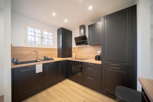 - une cuisine avec des placards noirs et un évier dans l'établissement hameau des pins, à Saint-Raphaël