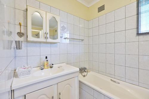 a white bathroom with a sink and a bath tub at Lily's Cottage in Durban