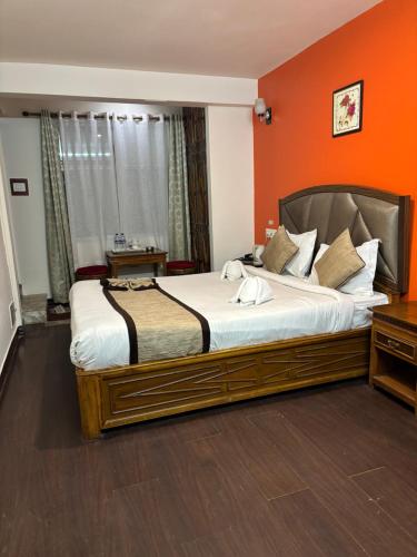 a bedroom with a large bed with an orange wall at Hotel KASTURI PALACE & RESTAURANT DARJEELING in Darjeeling