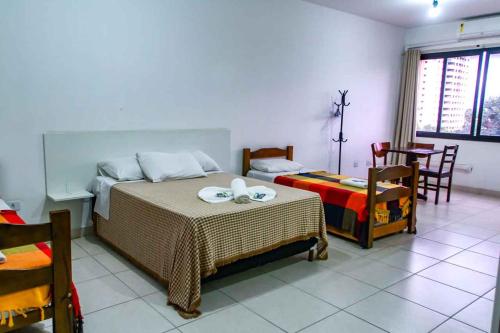 a bedroom with a bed and a table and chairs at Hotel Flamboyant Taubate in Taubaté