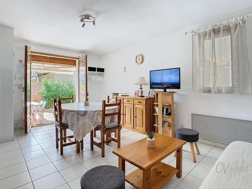un salon avec une table et une télévision dans l'établissement Maison Rayon du Soleil dans résidence privée avec piscine, à Vias