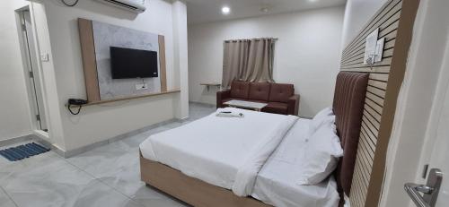 a bedroom with a bed and a chair and a television at Hotel Vaarahi Chanda Nagar, Near Hitech City in Hyderabad