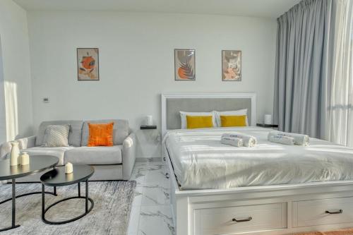 a white bedroom with a large bed and a couch at Chic Studio with Lagoon Views Walk Beach and Golf in Ras al Khaimah