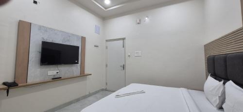 a bedroom with a bed and a tv on the wall at Hotel Vaarahi Chanda Nagar, Near Hitech City in Hyderabad