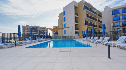 a swimming pool with lounge chairs and a building at Chic Studio with Lagoon Views Walk Beach and Golf in Ras al Khaimah