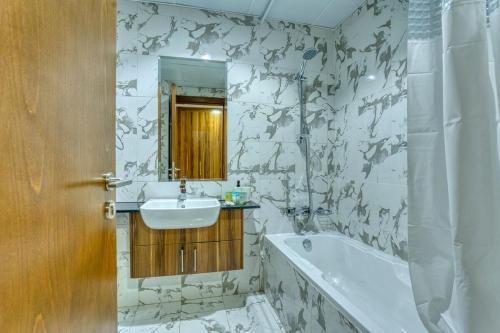 a bathroom with a sink and a tub and a mirror at Chic Studio with Lagoon Views Walk Beach and Golf in Ras al Khaimah