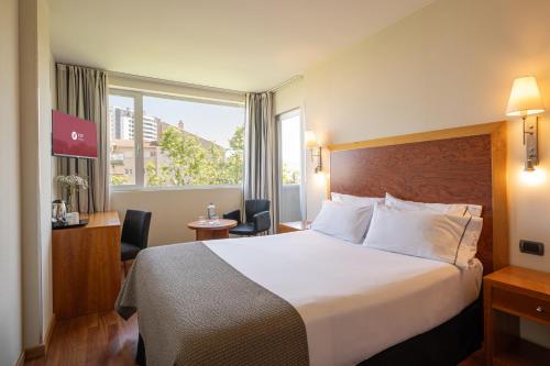 a hotel room with a large bed and a window at Exe Plaza Delicias in Zaragoza