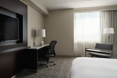 a hotel room with a bed and a desk and a television at Cleveland Marriott East in Warrensville Heights
