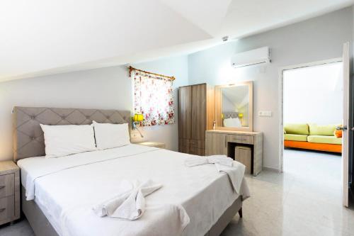 a bedroom with a large white bed and a yellow couch at Legend Of Dalyan Hotel in Dalyan