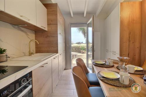 une cuisine avec une table et des chaises et une cuisine avec une fenêtre dans l'établissement Ty tourony, à Trégastel