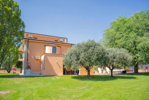 a building in a park with two trees in the grass at Villa Sun Kiss in Volta Mantovana