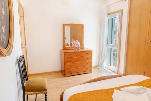 una camera da letto con un letto, uno specchio e una cassettiera di Sea & Soul a Costa da Caparica