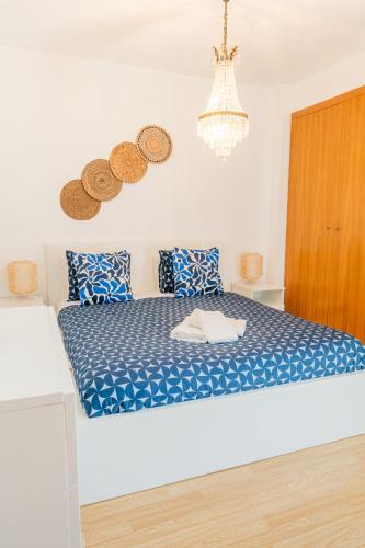 a bedroom with a bed with blue sheets and a chandelier at Sea & Soul in Costa da Caparica