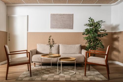 ein Wohnzimmer mit einer Couch und zwei Stühlen und einem Tisch in der Unterkunft BYPILLOW Erba in Girona