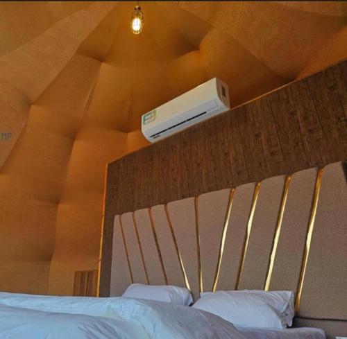 una camera da letto con un letto e un condizionatore a muro di Wadi Rum Sha ar Nights a Wadi Rum