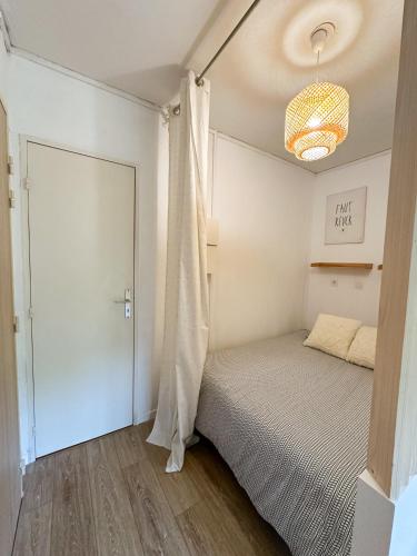 - une petite chambre avec un lit et un lustre dans l'établissement Studio wifi, parking privatif privé, clim, proche plage et polygone riviera, à Cagnes-sur-Mer