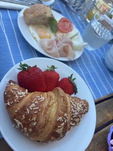 two plates of food with strawberries and croissants on a table at Hotel Villa Del Parco in La Maddalena