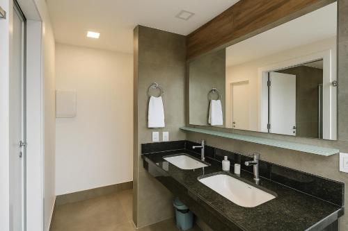 une salle de bain avec deux lavabos et un miroir dans l'établissement Ilusion Flat -Natal, à Natal