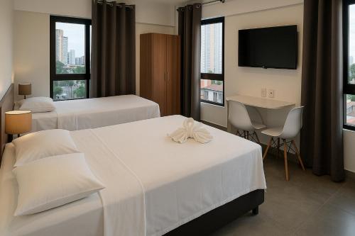une chambre d'hôtel avec deux lits et une télévision dans l'établissement Ilusion Flat -Natal, à Natal