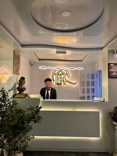 a man standing behind a counter in a restaurant at Hotel KASTURI PALACE & RESTAURANT DARJEELING in Darjeeling