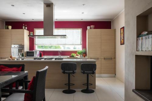 a kitchen with red walls and a counter with stools at A Casa Di Elena in Rigutino