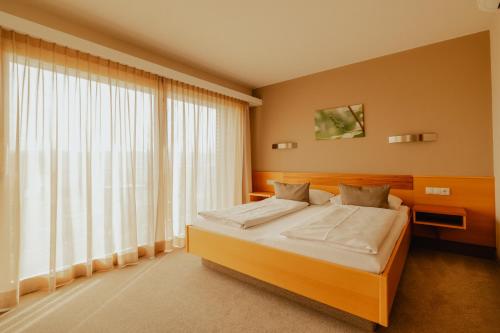 a bedroom with a bed and a large window at Weingut Kollerhof am Eichberg in Leutschach