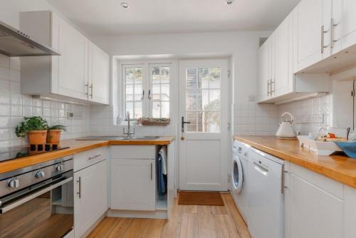 a white kitchen with wooden floors and white cabinets at Lulwind in Lulworth Cove