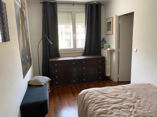 une chambre avec un lit, une commode et une fenêtre dans l'établissement Appartement design, à Boulogne-Billancourt