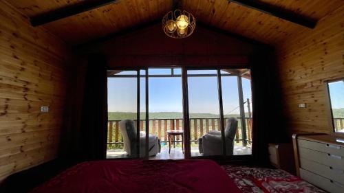 a bedroom with a bed and two chairs and a balcony at كوخ واستراحة شيخ الجبل in Ajloun