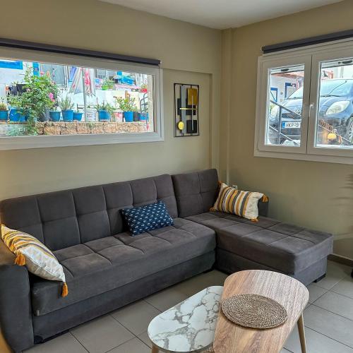 sala de estar con sofá marrón y 2 ventanas en Dolphin Apartment, en Stalida