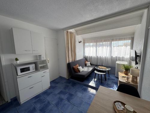 Il comprend une petite cuisine et un salon avec un canapé et une table. dans l'établissement Appartement 4 personnes à 50 m de la plage, à Narbonne