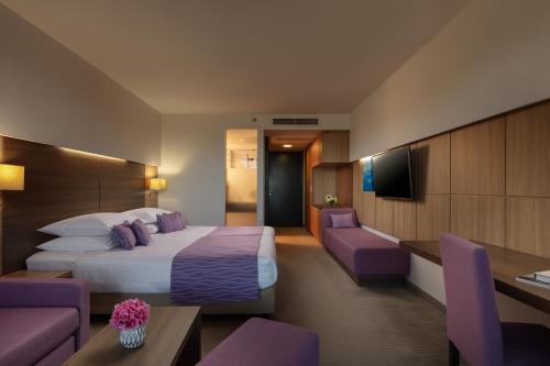 a hotel room with a large bed and purple furniture at Vitality Hotel Punta in Veli Lošinj