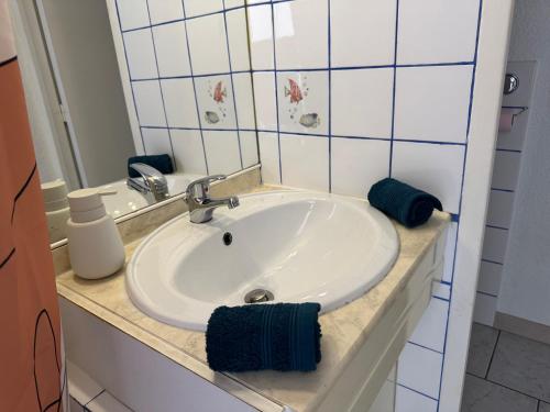 une salle de bain avec un lavabo blanc et un miroir dans l'établissement Appartement 4 personnes à 50 m de la plage, à Narbonne