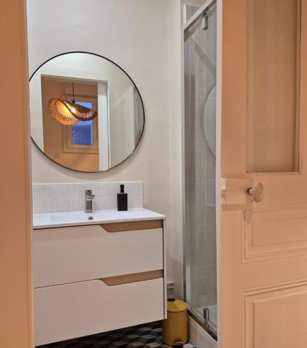 une salle de bain avec un lavabo et un miroir dans l'établissement Le cocon pop, à Reims