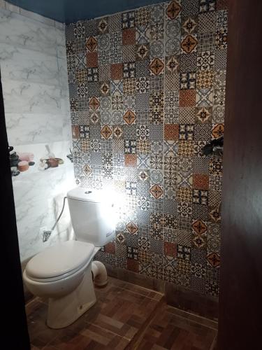 a bathroom with a toilet and a tiled wall at Gite d'étape La terre Amazigh in Amaskar