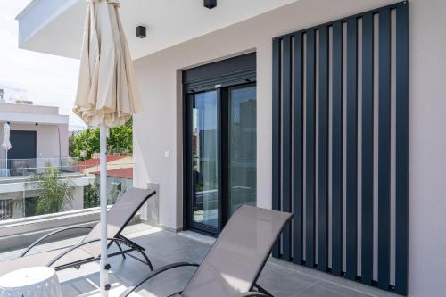 a balcony with two chairs and an umbrella at Nefeli & Nefeli Luxury Residential Complexes in Ofrínion