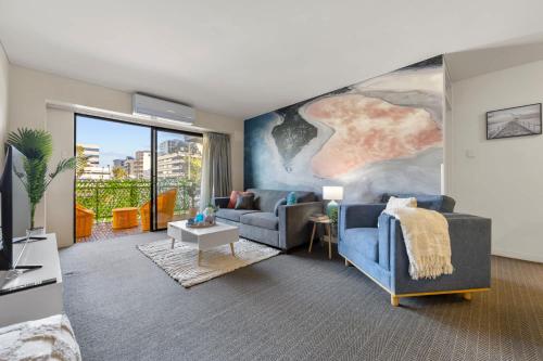 a living room with a blue couch and a painting at Stylish 2-Bedroom Apartment in the Heart of Perth in Perth