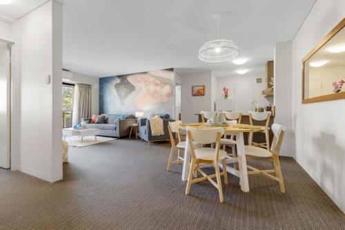 a dining room and living room with a table and chairs at Stylish 2-Bedroom Apartment in the Heart of Perth in Perth