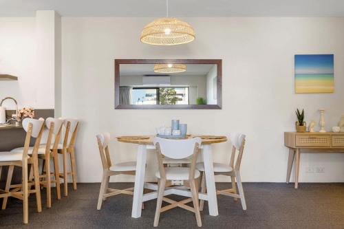 a dining room with a table and chairs and a mirror at Stylish 2-Bedroom Apartment in the Heart of Perth in Perth