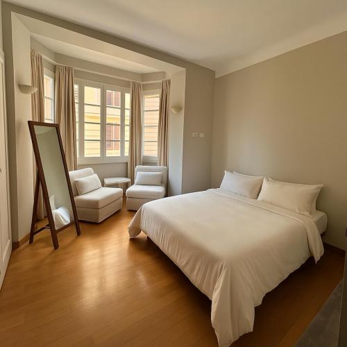 une chambre avec un grand lit blanc et une chaise dans l'établissement Charming Vintage Flat only 1 min walk from Monte Carlo, à Beausoleil