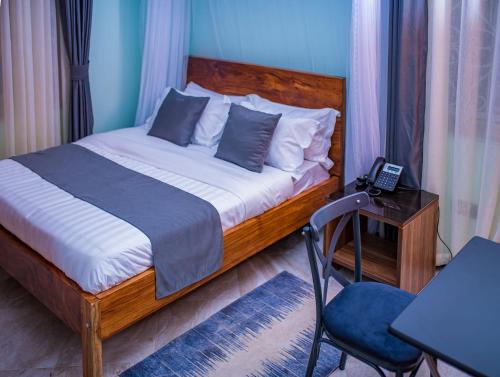 Schlafzimmer mit einem Bett und einem Schreibtisch mit einem Telefon in der Unterkunft The Georges Residence in Kabale
